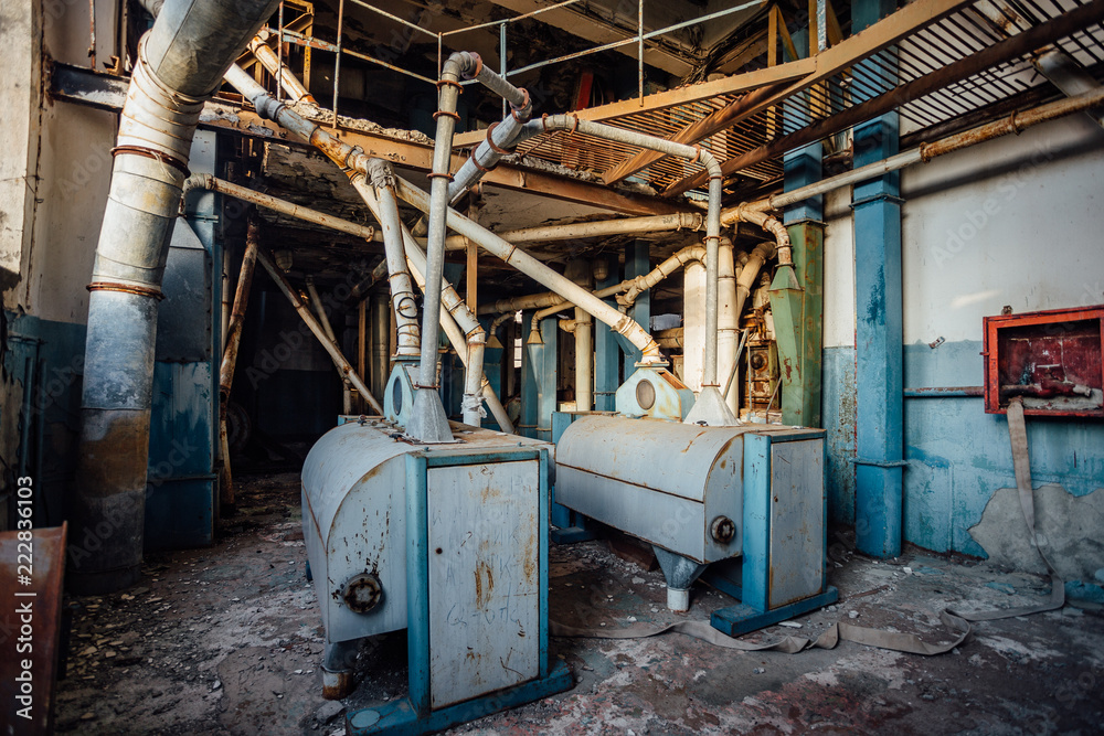 Abandoned flour milling factory. Old rusty roller mill equipment with pipeline
