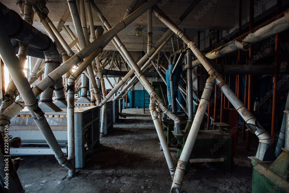 Abandoned flour milling factory. Old rusty roller mill equipment with pipeline Abandoned flour milling factory. Old rusty roller mill equipment with pipeline