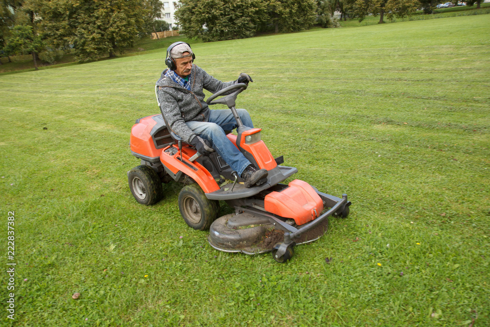 Fototapeta premium lawn mower tractor working in the town park