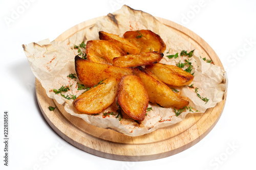 Fried potato wedges on a wooden tray board with paper isolated at white background.