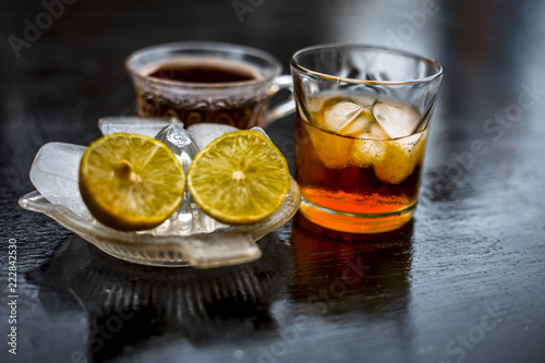 Close up of hangover remedy i.e. lemon juice and black tea in a transparent cup on wooden surface with Scotch or Scotch whiskey or Grain whiskey.
