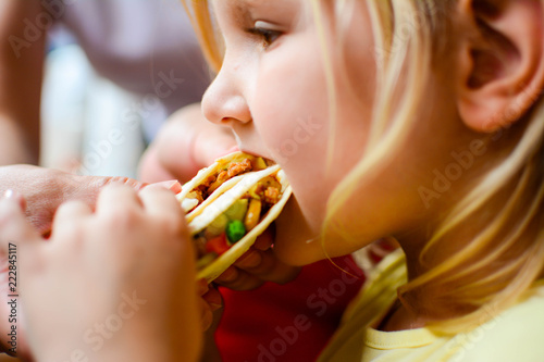 children  diet  culinary and food concept .Young blonde girl eating tortilla with meat and vegetables  mexican traditional snack concept