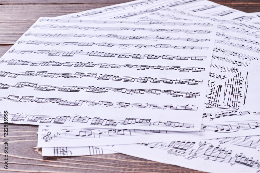 Naklejka premium Music score pages close up. Musical notes sheets on wooden background.