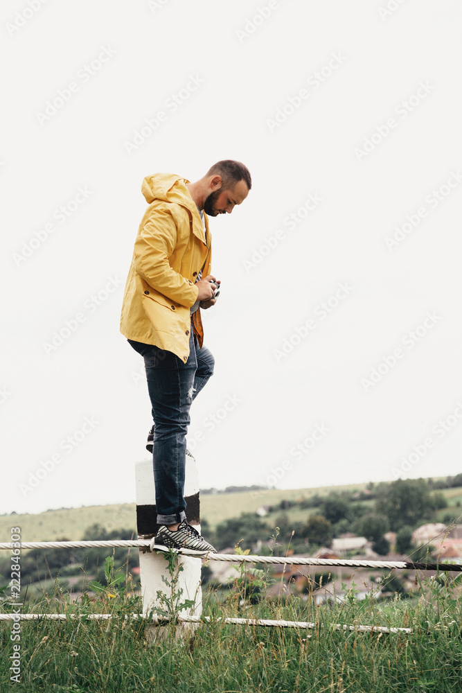 a man in a yellow raincoat with a camera a man in a yellow raincoat with a camera