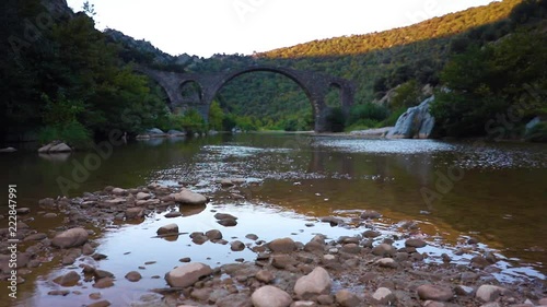 Cold water flowing in a stream under a medieval bridge photo