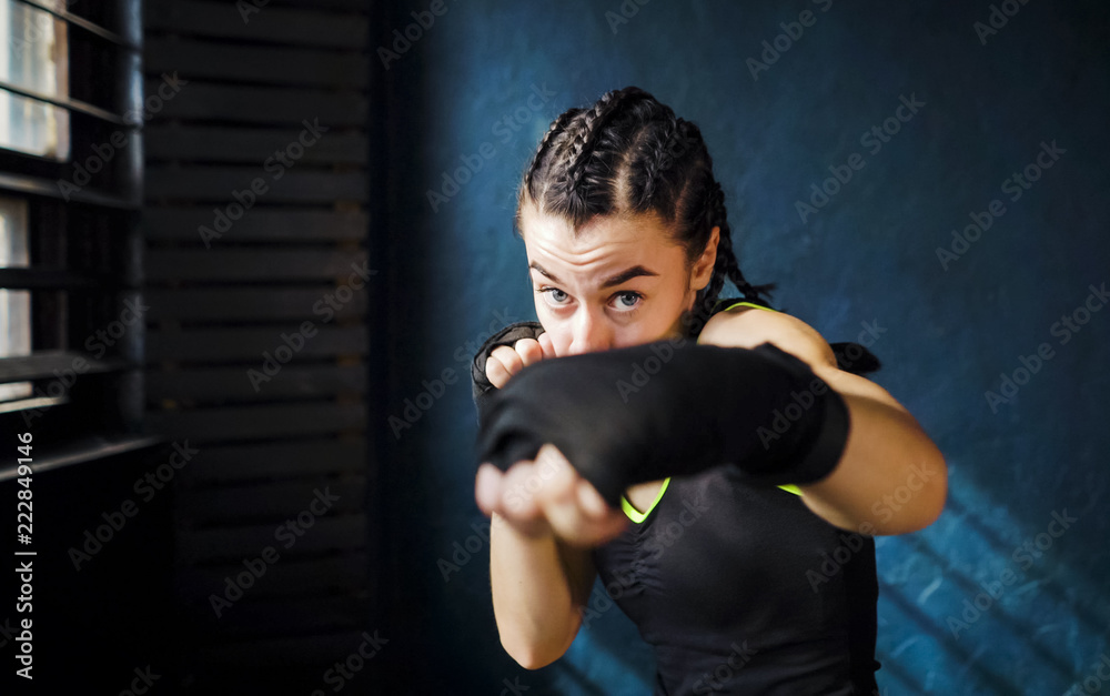 portrait beautiful young boxing woman training punching in gym. Fit female preparing to boxing competition. Wellness, fighting, motivation, martial arts, self defense concept