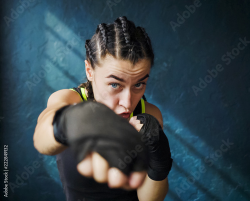 portrait beautiful young boxing woman training punching in gym. Fit female preparing to boxing competition. Wellness, fighting, motivation, martial arts, self defense concept