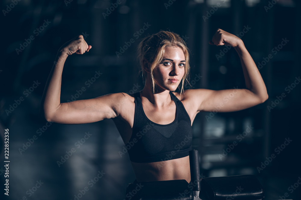 Attractive builder muscles women in fitness gym and looking camera
