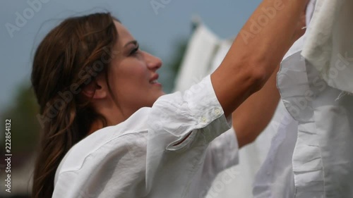 Woman Hanging Up Wet Laundry On Clothesline