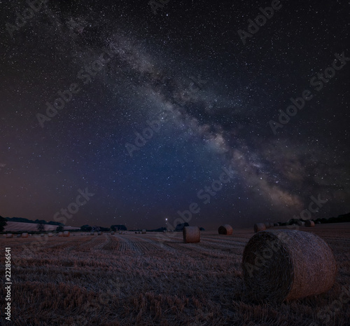 Vibrant Milky Way composite image over landscape of Lovely hay bales in English countryside