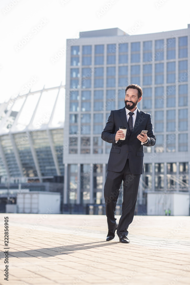 Full length of a cheerful bearded businessman walking in the city Full length of a cheerful bearded businessman walking in the city