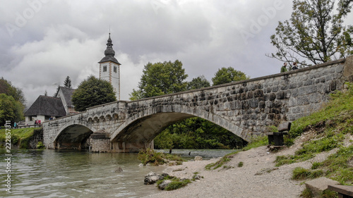 Church and bridge on Bohinj lake in slovenia. Very cloudy day