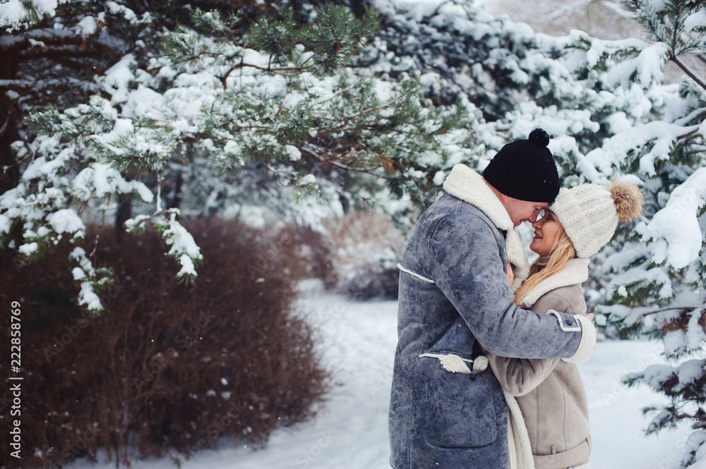 winter portrait of romantic couple kissing in snowy forest. Valentine's day or holiday concept.