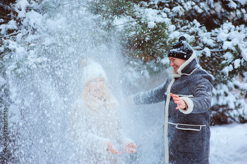 winter portrait of happy couple having lot of fun and throwing snow outdoor in the forest. Winter activities on holidays.