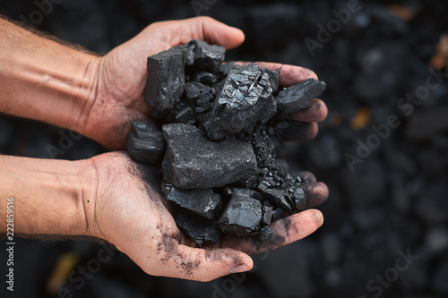 poor middle-aged man holding the hands of stone coal for sale to provide food for his family