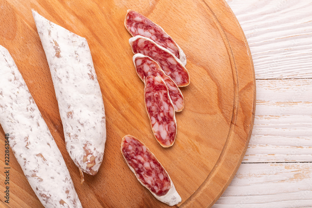 Salami on white wooden background. Top view. Copy space Salami on white wooden background. Top view. Copy space