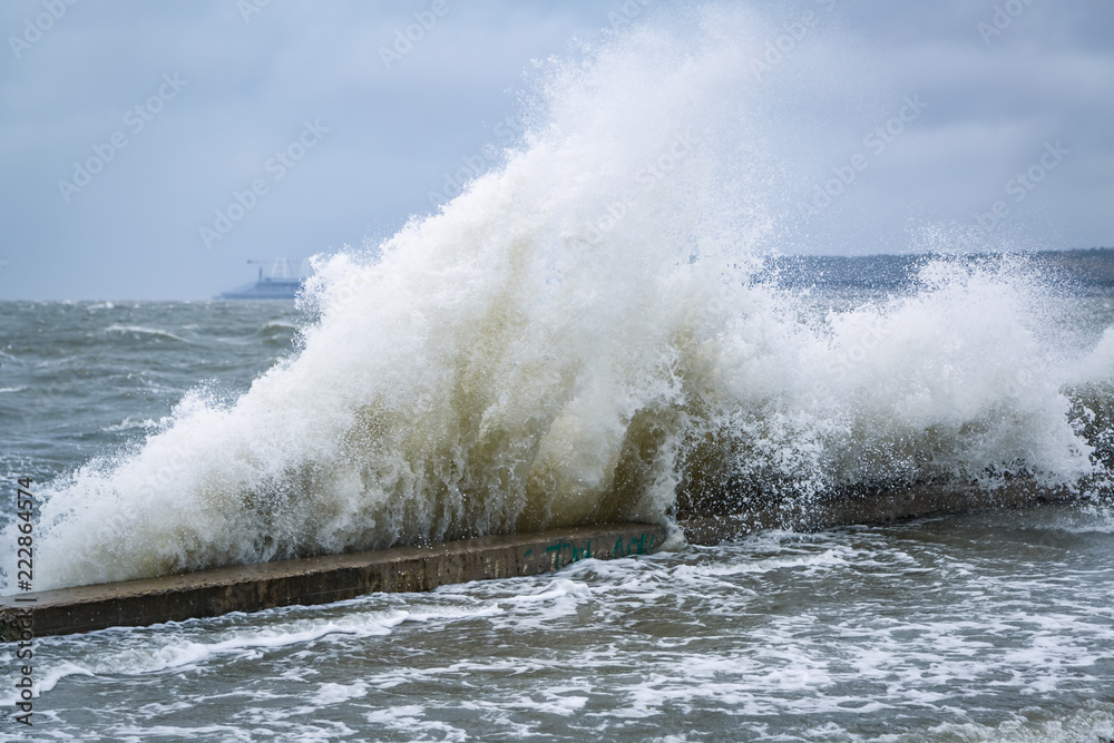 Large waves crash against the wall of the pier on the embankment of the resort city on the Black Sea