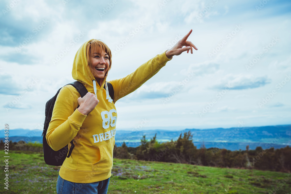 tourist traveler with backpack on background mountain blue sky clouds, hiker looking in distance, girl enjoying nature panoramic landscape and pointing hands, relax holiday mockup concept in trip tourist traveler with backpack on background mountain blue sky clouds, hiker looking in distance, girl enjoying nature panoramic landscape and pointing hands, relax holiday mockup concept in trip
