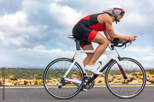 Cycling sport athlete man biking on triathlon bike. Fit male cyclist on professional triathlon bicycle wearing time trial helmet for ironman race. Exercising in Kailua Kona, Big Island, Hawaii, USA.