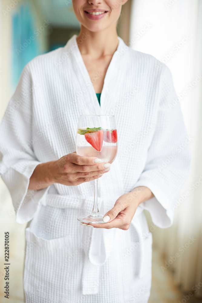 Healthy girl in white bathrobe enjoying time in spa center and having light strawberry cocktail Healthy girl in white bathrobe enjoying time in spa center and having light strawberry cocktail