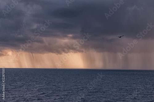 dense rain clouds and a tornado over the sea