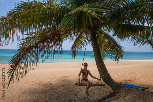 Happy woman relaxing in hammock on a tropical beach