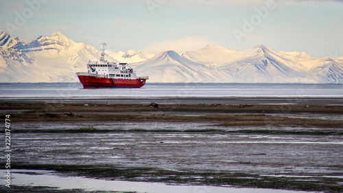 An icebreaker ship sits offshore in front of snow-covered mountains in Longyearbyen, Svalbard, Norwegian Arctic