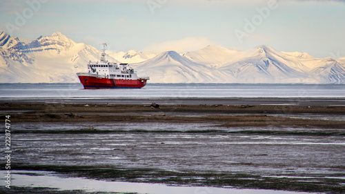 Obraz na płótnie An icebreaker ship sits offshore in front of snow-covered mountains in Longyearb