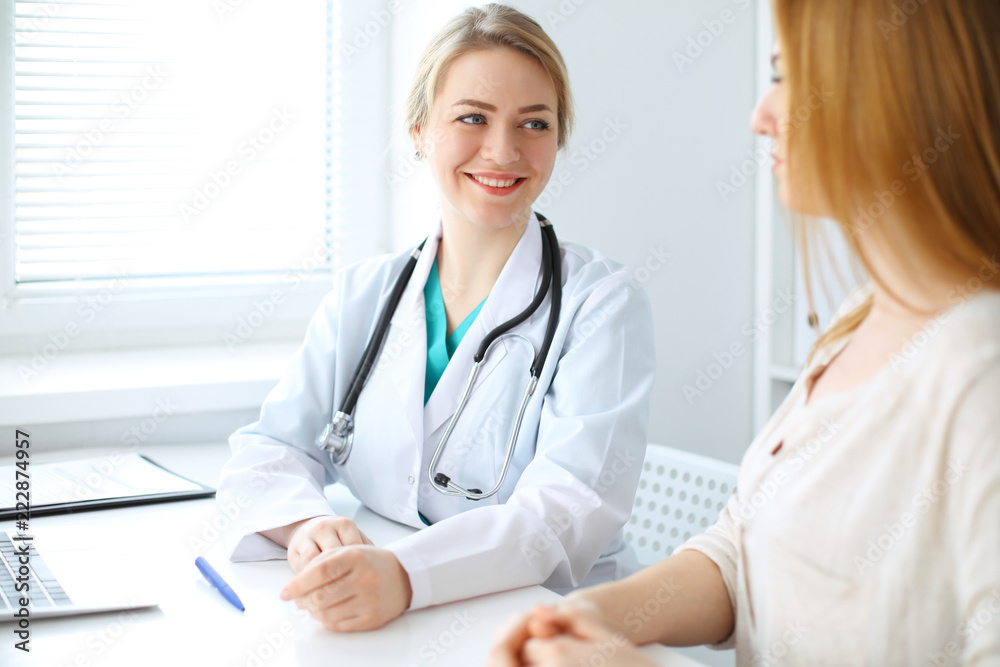 Doctor and patient discussing something while sitting at the desk at hospital. Medicine and health care concept Doctor and patient discussing something while sitting at the desk at hospital. Medicine and health care concept