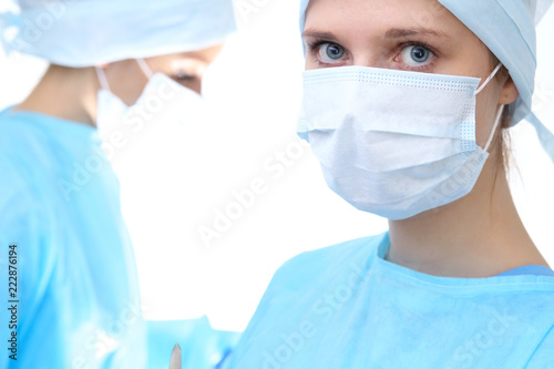 Surgeon doctor in mask performing operation. Focus on female intern girl. Medicine, emergency help concepts