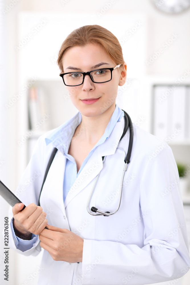 Young brunette female doctor at work in hospital. Physician ready to help. Medicine and healthcare concept Young brunette female doctor at work in hospital. Physician ready to help. Medicine and healthcare concept