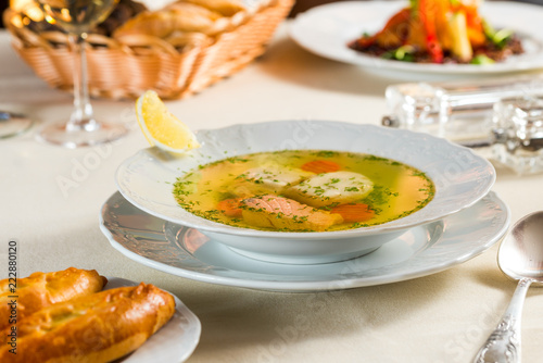 Fresh fish soup in a white plate with specialties and sauces and homemade bread
