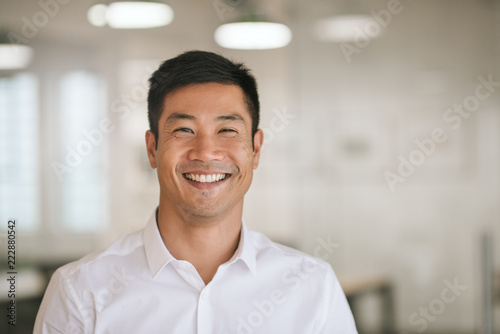 Young Asian businessman standing in an office smiling confidently