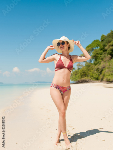 beautiful young woman standing on the sand coast in sunny Thailand