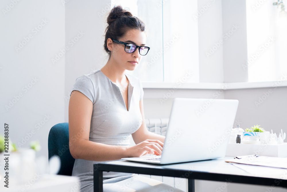 Portrait of beautiful young woman wearing glasses using laptop sitting at table in cafe, copy space Portrait of beautiful young woman wearing glasses using laptop sitting at table in cafe, copy space