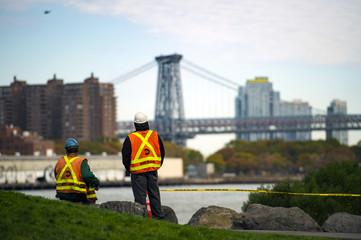 Two NYC Transit workers are taking a break from work and watching the  beautiful Manhattan skyline in New York, USA.