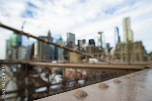 Blurred Manhattan skyline seen from the beautiful Brooklyn bridge. Cloudy day in New York City, USA.
