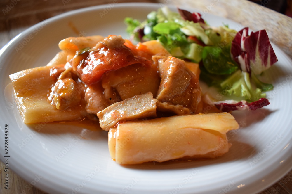 Pasta with meat tomato sauce and salad of green vegetables on a white plate Pasta with meat tomato sauce and salad of green vegetables on a white plate