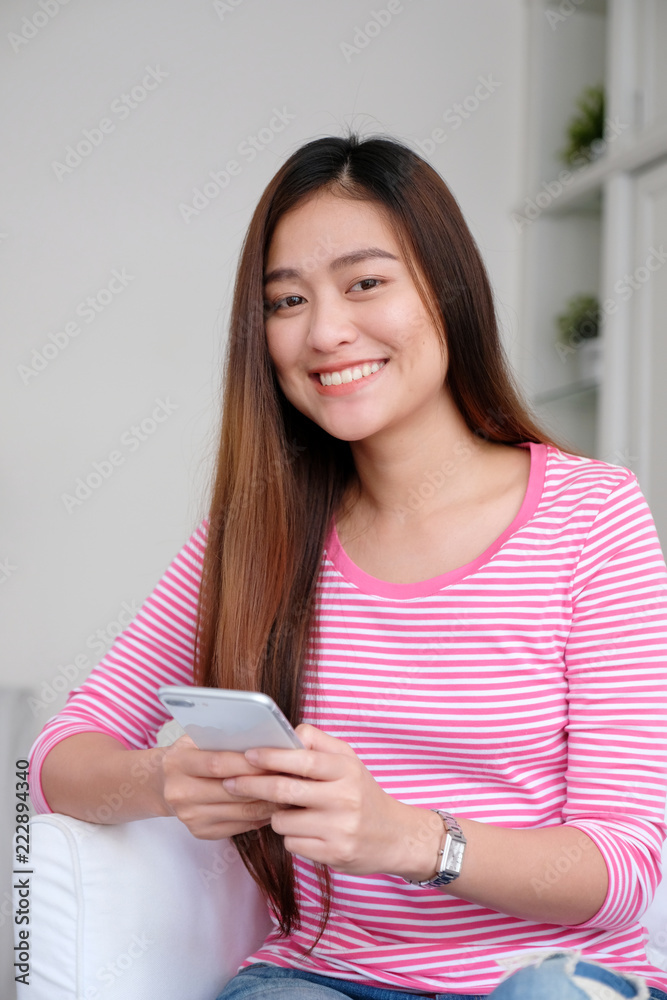 Young asian woman using smart phone with smiling, happy and relax emotion in white room background, people on phone, lifestyle Young asian woman using smart phone with smiling, happy and relax emotion in white room background, people on phone, lifestyle