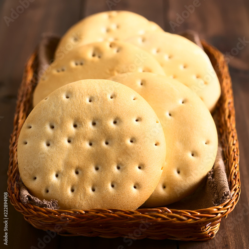 Traditional Chilean Hallulla bread rolls in basket, photographed on dark wood with natural light (Selective Focus, Focus on the first roll) photo