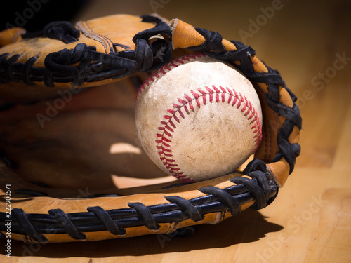 Canvas Print Close up sports background image of an old used weathered leather baseball with red laces inside of a baseball glove or mitt showing intricate detailing and black leather lacing