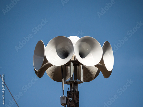 Close up photograph of several multi directional round amplified emergency siren  or noon time horns on top of a wooden pole in a small town in Wisconsin.