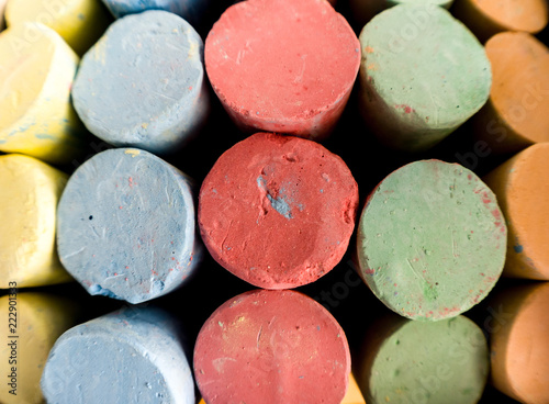 Close up background photograph image of colorful sidewalk chalk including red, green, blue, yellow and orange organized in rows by color.