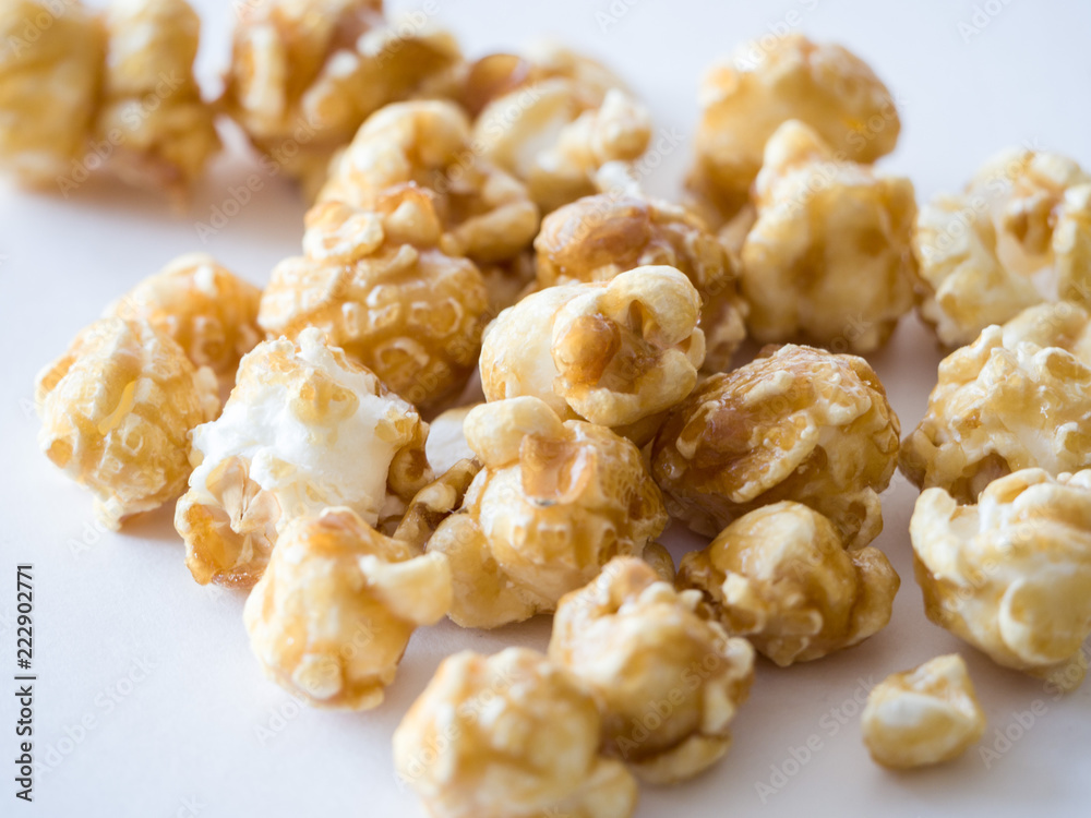 Close up macro photograph of isolated pile caramel popped popcorn kernel pieces at center of image with white space below for delicious looking background or wallpaper image.