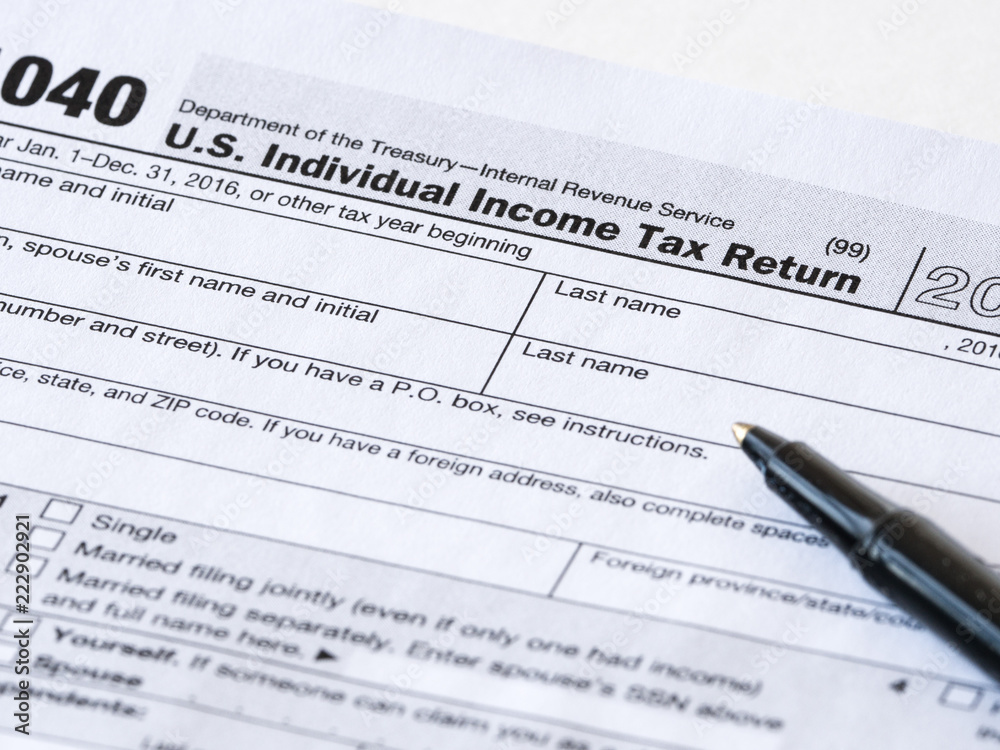Close up photograph of United States 1040 individual income tax return form with a black ballpoint pen perfect for tax day or tax season background or wallpaper image. Close up photograph of United States 1040 individual income tax return form with a black ballpoint pen perfect for tax day or tax season background or wallpaper image.