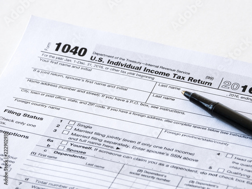 Close up photograph of United States 1040 individual income tax return form with a black ballpoint pen perfect for tax day or tax season background or wallpaper image.