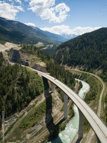 Aerial view of a bridge over a river in the Canadian Rockies during a vibrant sunny summer day. Located in British Columbia, Canada.