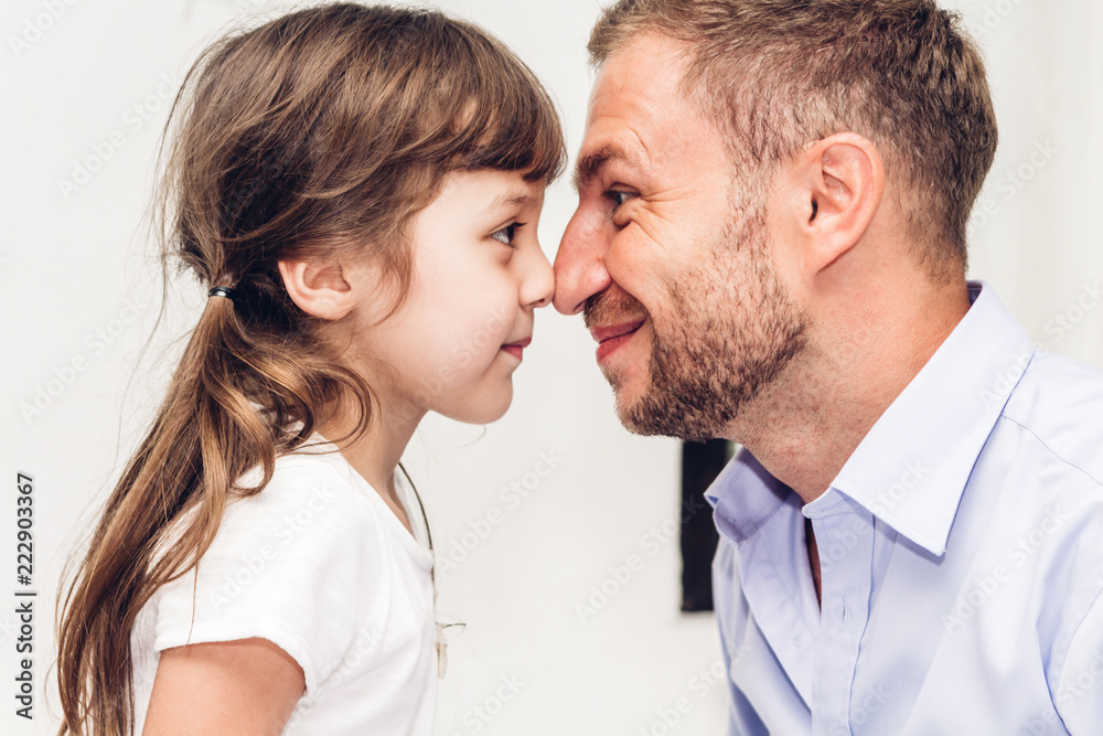 Little girl with dad smiling and touching nose together at home.Love of family and father day concept Little girl with dad smiling and touching nose together at home.Love of family and father day concept