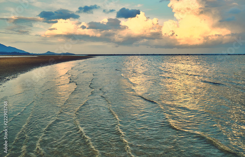 Sandy beach at spectacular sunset. Reflections in water.    