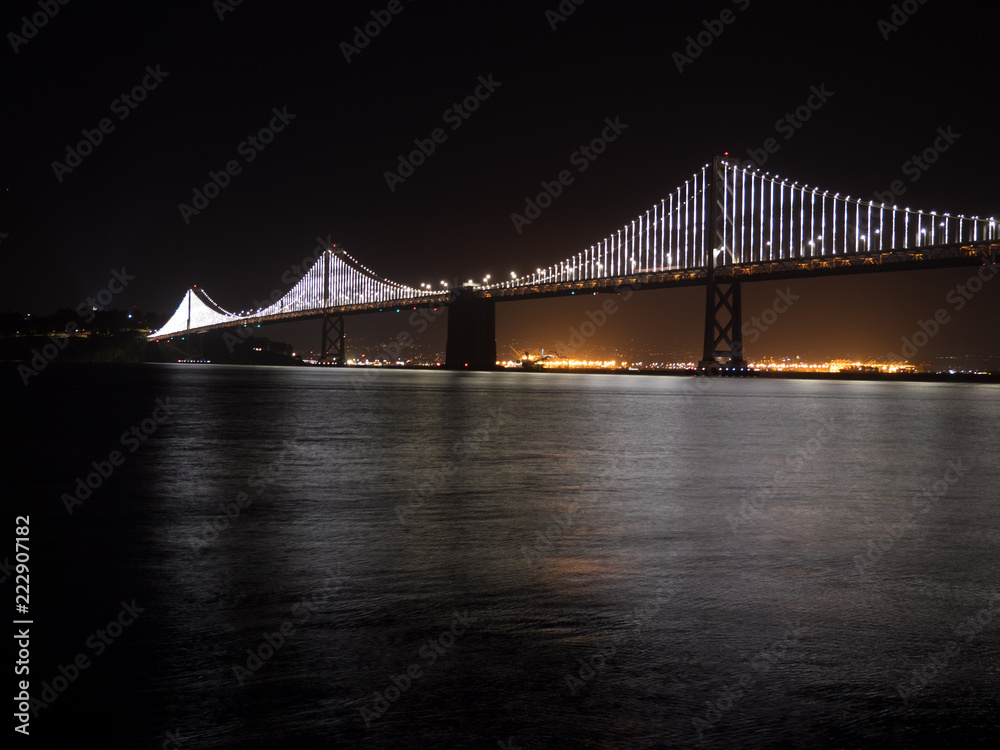 Bridge Lights on the San Francisco Oakland Bay bridge at night with water below.